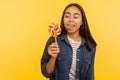 Portrait of happy carefree girl in denim shirt standing with tongue out, dreaming and tempted to taste lollipop