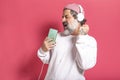 Portrait of happy carefree handsome urban style middle aged man in casual t-shirt dancing along to music holding smartphone