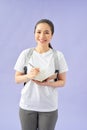 Portrait of a happy casual girl student with backpack writing in a notepad while standing with books isolated over purple Royalty Free Stock Photo