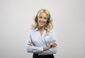 Portrait of happy caucasian call centre operator with headset crossing arms and smiling at camera, light background Royalty Free Stock Photo