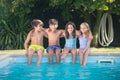 Portrait of happy Caucasian children wetting their legs in pool