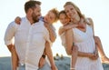 Portrait of a happy caucasian couple carrying their kids on their back at the beach. Smiling mother and father piggyback Royalty Free Stock Photo