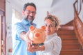 Portrait of happy caucasian couple holding piggy bank to save money to make their future dreams come true. Husband and wife