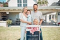 Portrait of happy caucasian family holding for sale and sold sign while relocating and moving in new house. Smiling Royalty Free Stock Photo