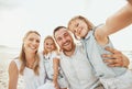 Portrait of happy caucasian family taking selfies while enjoying a fun summer vacation together at the beach. Loving Royalty Free Stock Photo