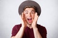 Portrait of happy Caucasian male exclaims joyfully, keeps mouth opened, wears elegant hat and t shirt, being in high spirit, isola