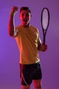 Portrait of happy caucasian male tennis player with tennis racket over neon pink lighting Royalty Free Stock Photo