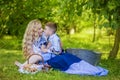 Portrait of Happy Caucasian Mother Kissing Her Little Kid. Posing with Basket Full of Bread Rings Outdoors Royalty Free Stock Photo