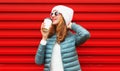 Portrait happy caucasian smiling young woman with cup of coffee posing wearing a white hat on red background Royalty Free Stock Photo