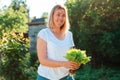 Portrait of a happy caucasian woman holding a bunch of freshly picked lettuce. The concept of harvesting and gardening Royalty Free Stock Photo