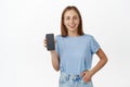 Portrait of happy caucasian woman showing mobile phone screen, smiling satisfied, recommending app, good smartphone Royalty Free Stock Photo