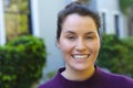 Portrait of happy caucasian woman standing and smiling in front of house in garden Royalty Free Stock Photo