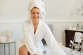 Portrait of happy caucasian woman wearing robe, running bath and similing in bathroom