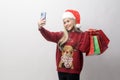 Portrait of happy Caucasian young woman in santa claus hat with  shopping bags over white background Royalty Free Stock Photo