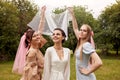 Portrait of happy charming bride in a white dress with a white veil and two bridesmaids in a blue and beige dress