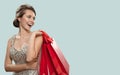 Portrait of happy charming woman holding red shopping bags. Blue