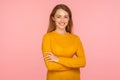 Portrait of happy cheerful ginger girl in sweater standing with arms crossed and looking at camera with toothy smile Royalty Free Stock Photo