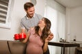 Happy cheerful husband giving present box to his pregnant wife Royalty Free Stock Photo