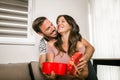 Happy cheerful husband giving present box to his pregnant wife Royalty Free Stock Photo