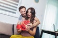 Happy cheerful husband giving present box to his pregnant wife Royalty Free Stock Photo