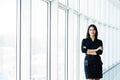 Attractive smiling young business woman. Portrait of happy cheerful young lady with crossed arms on business center window backgro Royalty Free Stock Photo