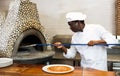 Portrait of happy chef getting ready pizza out of oven in kitchen