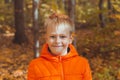 Portrait of happy child boy in orange jacket in autumn park. Fall season and children concept Royalty Free Stock Photo