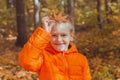 Portrait of happy child boy in orange jacket in autumn park. Fall season and children concept Royalty Free Stock Photo