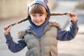 Portrait of happy child girl with hair braids in warm clothes in autumn outdoors Royalty Free Stock Photo