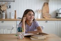 Portrait of happy child schoolgirl sitting at table with textbooks at home doing school homework Royalty Free Stock Photo