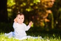 Portrait of happy child sitting on the meadow and holds snack in the park. Royalty Free Stock Photo