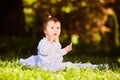 Portrait of happy child sitting on the meadow and holds snack in the park. Royalty Free Stock Photo