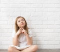 Portrait of a happy child - a small blonde girl 8-9-10 years old, sitting on the floor against the background of an empty white Royalty Free Stock Photo