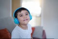 Portrait of happy child wearing headphones and looking up with smiling face,Happy young boy listening to music, Cute Kid sitting Royalty Free Stock Photo