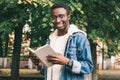 Portrait happy clever young african man student with a book looking away wearing an eyeglasses in autumn city park Royalty Free Stock Photo