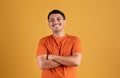 Portrait of happy confident brazilian man standing with folded arms and smiling, posing over yellow studio background Royalty Free Stock Photo