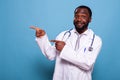 Portrait of happy confident medic wearing white lab coat and stethoscope pointing both hands with index fingers Royalty Free Stock Photo