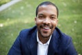 Portrait of happy confident young African-American businessman in formal wear sitting at city park.Blurred background Royalty Free Stock Photo