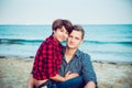 Portrait of Happy couple on the beach. Young man and woman sitting on sandy coast and hugging. Concept of lovers happy moments on Royalty Free Stock Photo