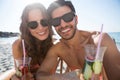 Portrait of happy couple holding drinks at beach Royalty Free Stock Photo