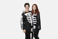 Portrait of happy couple in skeleton costume against gray background