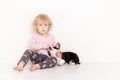 Portrait of a happy curly cute Caucasian little girl at home with a welsh corgi cardigan puppy playing on the floor in