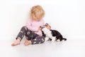 Portrait of a happy curly cute Caucasian little girl at home with a welsh corgi cardigan puppy playing on the floor in