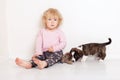 Portrait of a happy curly cute Caucasian little girl at home with a welsh corgi cardigan puppy playing on the floor in the room