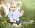 A portrait of a happy cute baby boy sitting on green grass outdoor at summer day. Emotions, smile, grimace, surprise, delight, kid Royalty Free Stock Photo