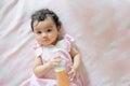 Portrait of happy cute little Asian baby girl lying in bed holding a bottle of orange juice. Smile and look at the camera baby Royalty Free Stock Photo