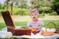 Portrait of a happy cute little Asian baby girl sitting smiling on lawn holding orange fruit with basket while relaxing picnic in Royalty Free Stock Photo