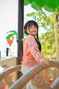 Happy and cute little Asian girl enjoys playing on playground in the city summer park Royalty Free Stock Photo