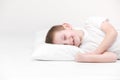 Portrait of a happy cute little boy waking up in the morning and lying on a white pillow isolated on a white background. fresh and Royalty Free Stock Photo