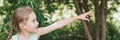 Portrait of a happy cute little caucasian seven year old kid gir, pointing to the side on the background of nature. explore the wo Royalty Free Stock Photo